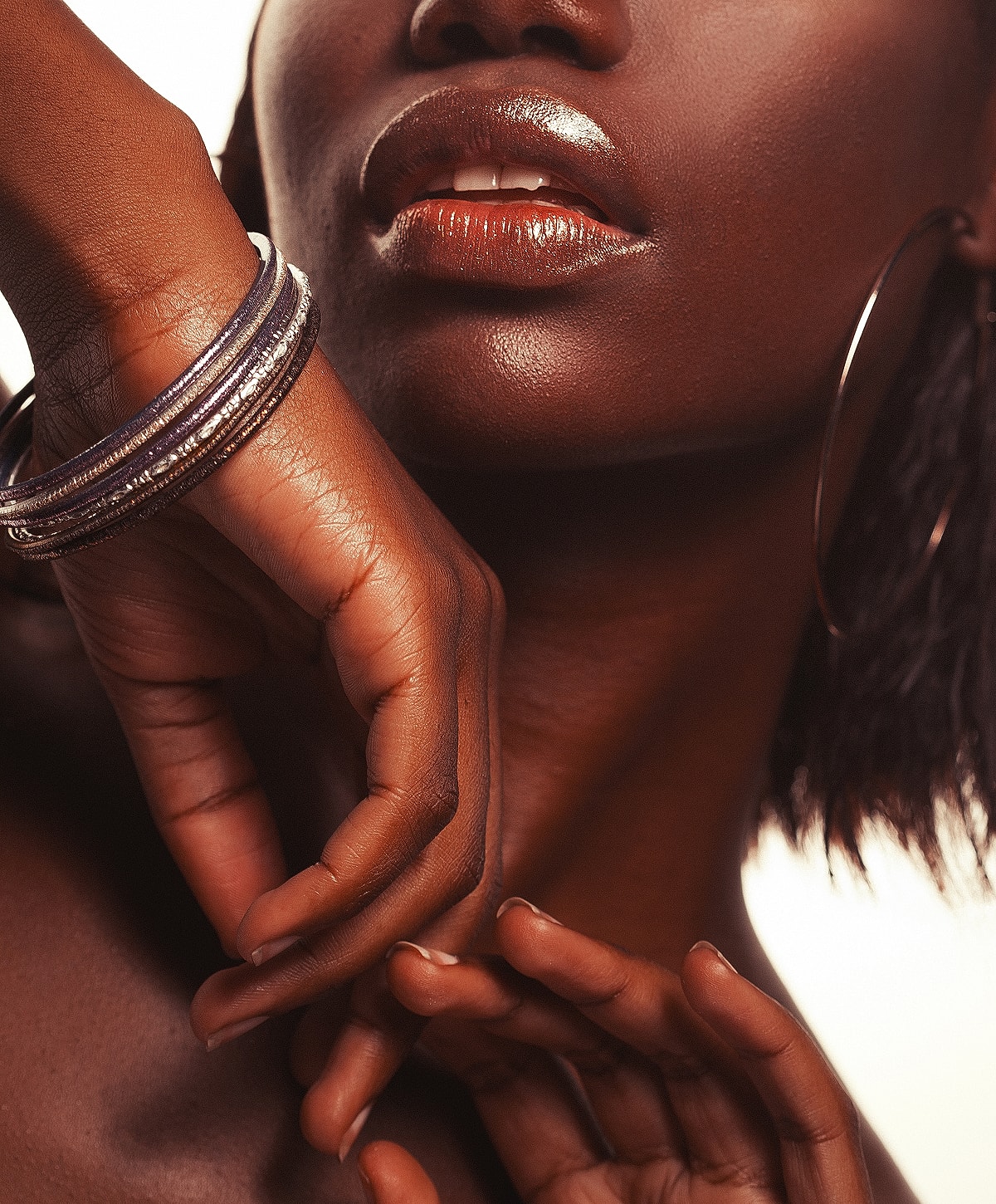 Close-up of hands and lips with jewelry.