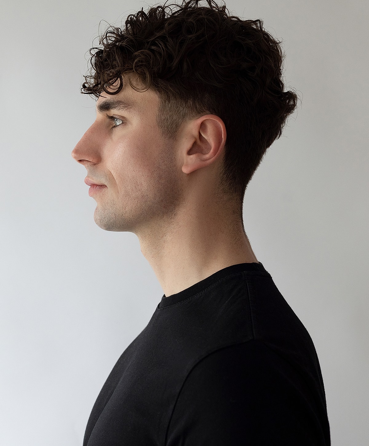 Profile of a young man with curly hair.