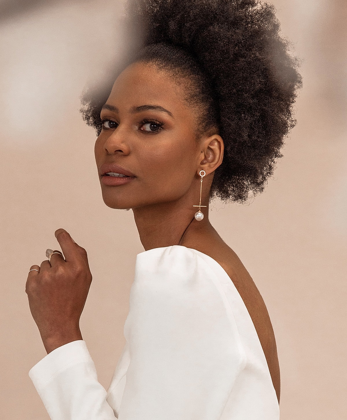 Model with curly hair and elegant jewelry.