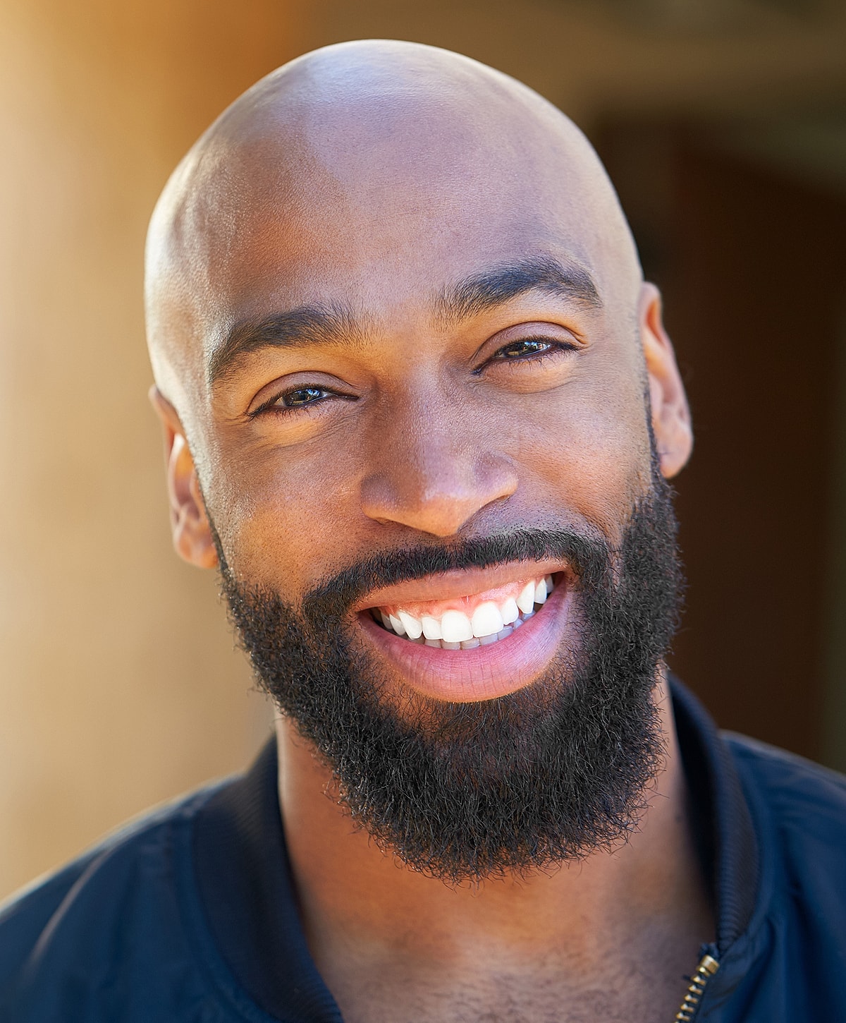 Smiling man with a bald head and beard.