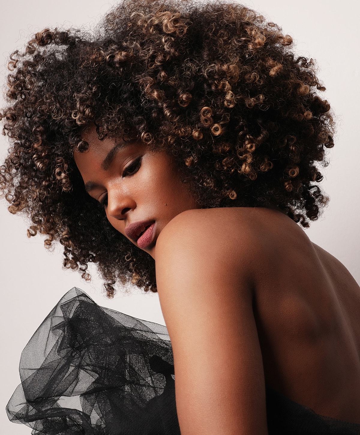 Woman with curly hair and sheer black fabric.