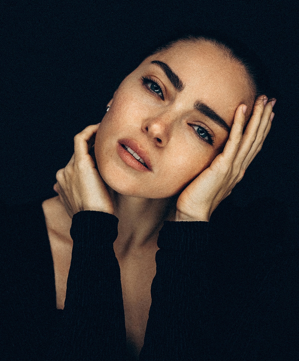 Woman with thoughtful expression against dark background