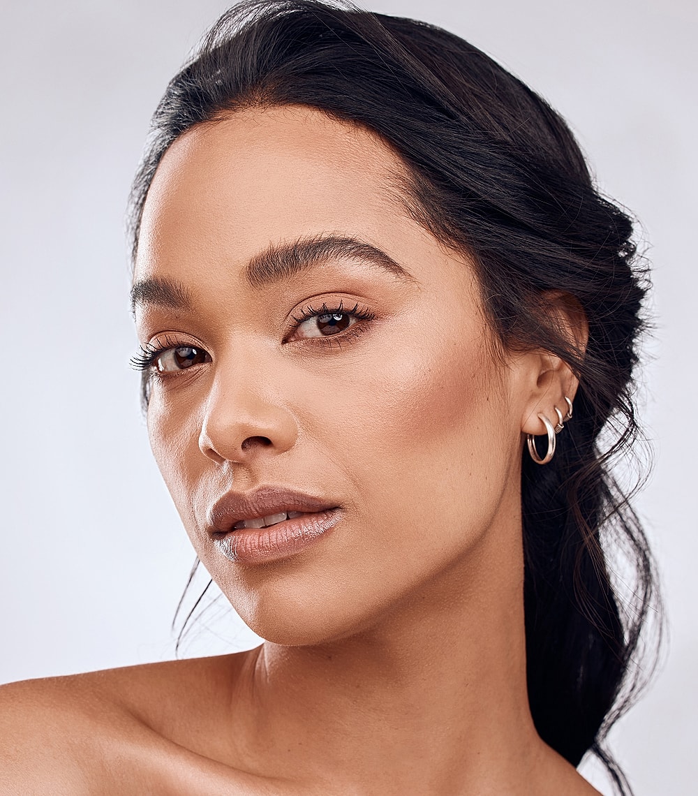 Woman softly touching her face, thoughtful expression.