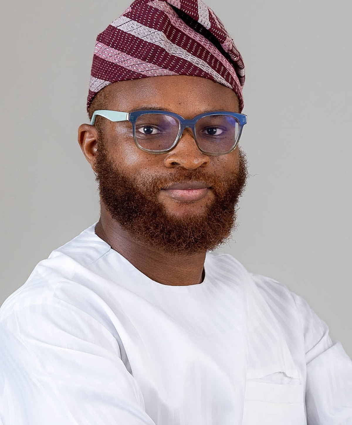 Man in traditional attire with glasses and beard.