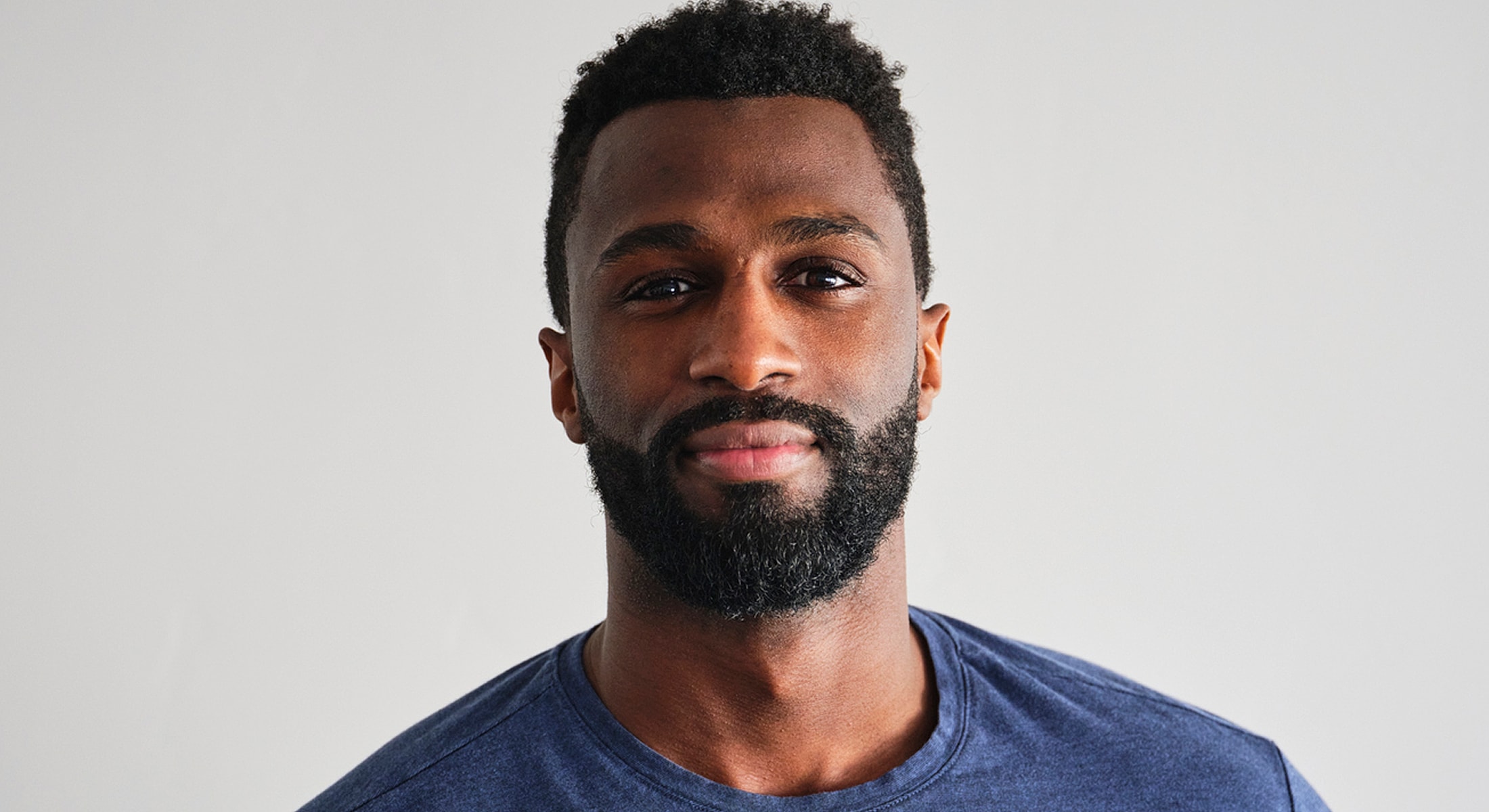Smiling man with beard wearing a blue shirt.