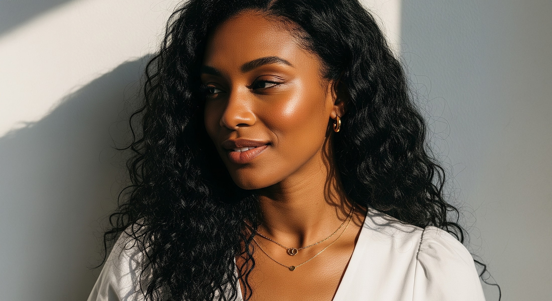 Woman with curly hair smiling in natural light.
