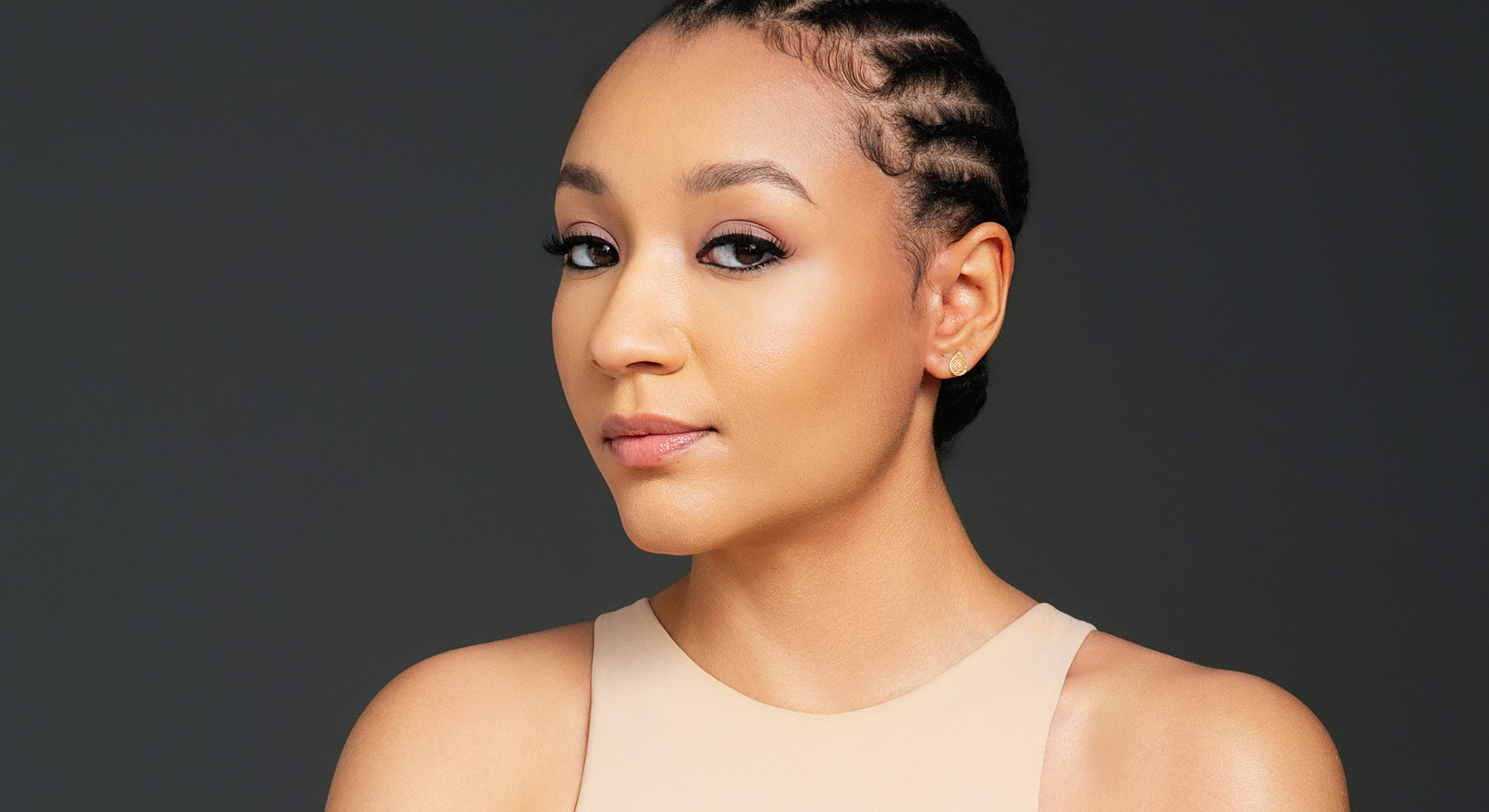 Woman with braided hair against dark background.