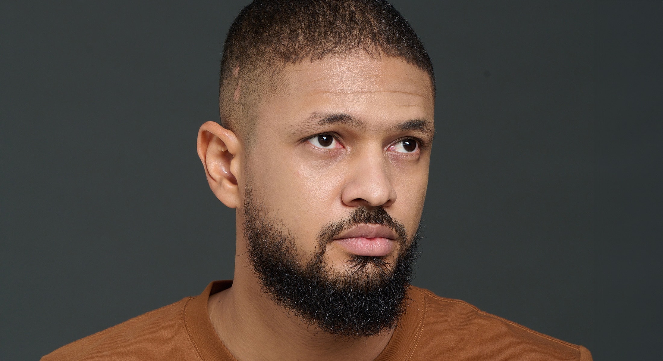 Man with beard looking thoughtfully to the side.