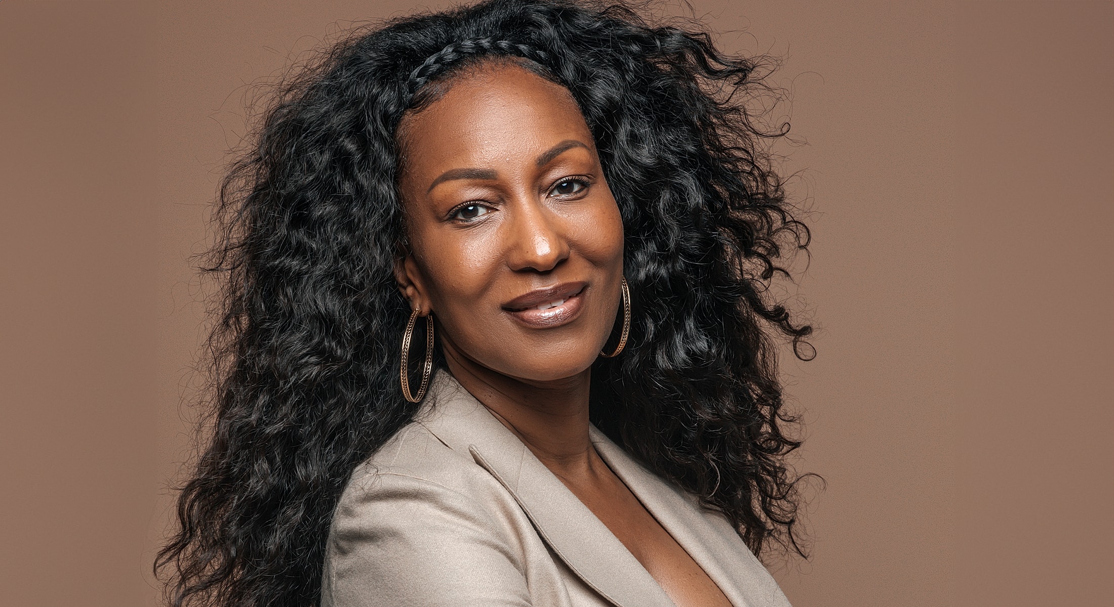 Smiling woman with curly hair and earrings.