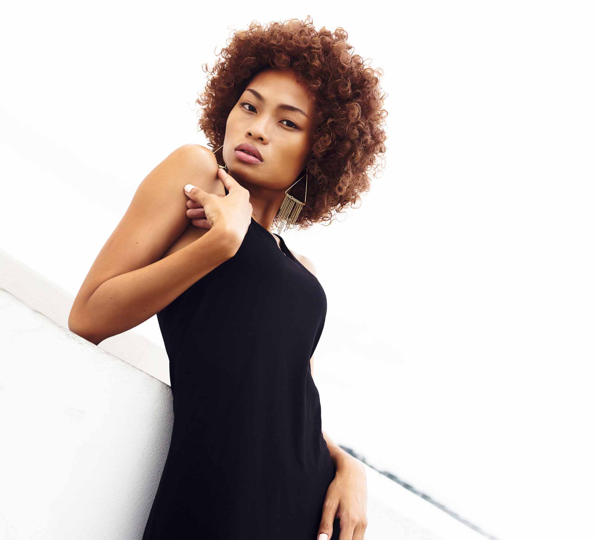 woman with short curly hair and triangle earrings