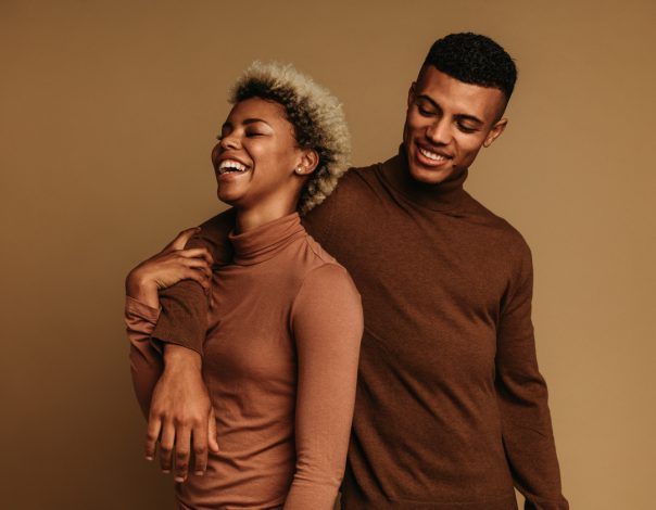 Fashionable african american couple standing together. Smiling couple in love together on brown background.
